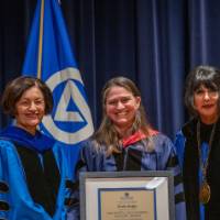 Provost Mili and President Mantella smile for picture with woman on stage